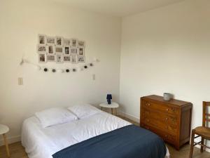 una camera da letto con un letto e una cassettiera in legno di Maison ROMERO a Plénée-Jugon