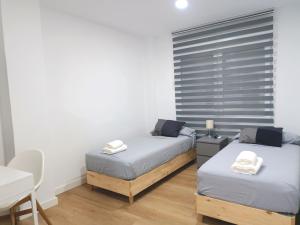 2 łóżka pojedyncze w pokoju ze stołem i biurkiem w obiekcie Casa de Huéspedes 12 Octubre Rooms w Madrycie