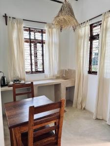 - une cuisine avec une table et deux chaises et des fenêtres dans l'établissement Chokoro House, à Paje