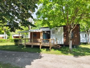 a tiny house with a tree in the yard at Camping Roc de l'Arche in Espalion