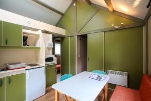 シノンにあるVillage Vacances Les Fontenilsの緑の壁のキッチン(テーブル、椅子付)
