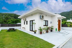 a white house with a green lawn at Anew villa on Tokashiki island, walk to the beach in Awaren