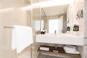 a white bathroom with a sink and a mirror at Crowne Plaza - Caparica Lisbon in Costa da Caparica