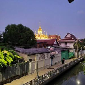 a building next to a river with a building in the background at auntythong house in Bangkok