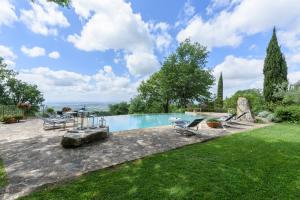 a swimming pool in a yard with two chairs at Villa Tregole by Mmega in Fonterutoli