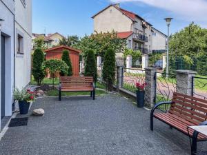 two benches sitting in a courtyard with buildings at Szafir Ustka in Ustka