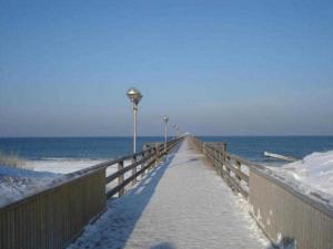 a boardwalk leading to the ocean with snow on it at Kastanienallee zwischen Zentrum und Seebrücke in Graal-Müritz