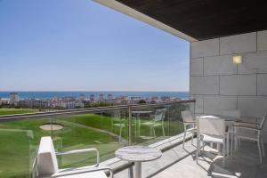 a balcony with white chairs and a view of the ocean at Crowne Plaza - Caparica Lisbon in Costa da Caparica