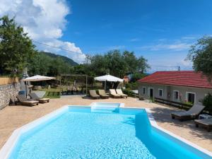 a pool in a yard with chairs and a house at Olive Grove Poolside Apartments in Benitses