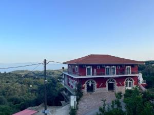 a large red house on top of a hill at Anthoussa Rooms in Parga +45 photos