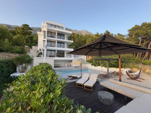 a house with a swimming pool and an umbrella at Soho Apartments Brela in Brela