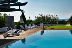 a group of chairs sitting next to a swimming pool at Seafront Villa Layla by Ruidoso Luxury in Ayia Napa