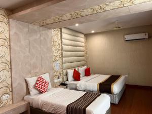 two beds in a hotel room with red pillows at Hotel Ratana International in Lucknow