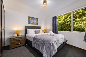 a bedroom with a bed and a window at Lake Views - Close to Town - Hot Tub - Spa Pool in Queenstown