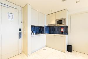 a kitchen with white cabinets and a microwave at Crowne Plaza - Caparica Lisbon in Costa da Caparica