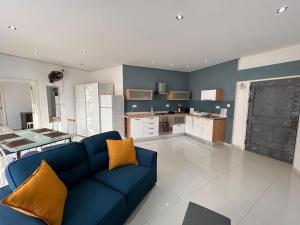 a living room with a blue couch and a kitchen at Modern Studio in Mgarr Malta in Mġarr