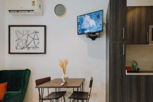 The Avery Studio at Embassy Gardens, Cantonments في آكرا: غرفة معيشة مع طاولة وتلفزيون على الحائط