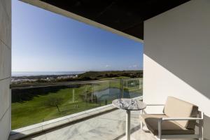 a room with a large window with a chair and a table at Crowne Plaza - Caparica Lisbon in Costa da Caparica