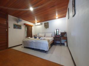 Bunaken Villa Queen's Dive في بوناكن: غرفة نوم بها سرير وسقف خشبي +51 صورة