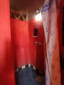 czerwona łazienka z czerwoną ścianą i prysznicem w obiekcie Merzouga Natural Luxury Camp w mieście Merzouga