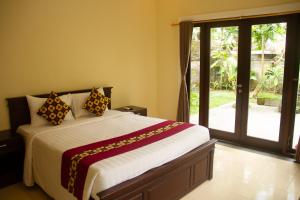 a bedroom with a bed and a sliding glass door at Sekar Waru Homestay in Sanur