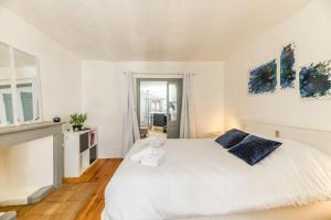 a white bedroom with a large white bed with blue pillows at La Salamandre, 40 m2, 1 chambre, 2 pas de la gare in Voiron
