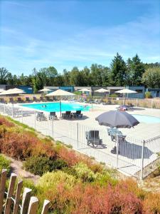 a swimming pool with umbrellas and tables and chairs at Terres de France - Le Domaine du Moulin Neuf in Rochefort-en-Terre