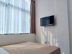 a room with a tv on the wall next to a window at Themas Guest House in Jakarta +31 photos