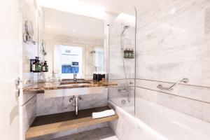 a bathroom with a tub and a sink and a shower at Crowne Plaza - Caparica Lisbon in Costa da Caparica