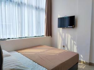 a room with a bed and a tv on a wall at Themas Guest House in Jakarta