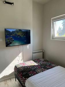 a bedroom with a bed and a tv on the wall at Apartament ogrodowy in Miechów