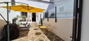 eine Terrasse mit einem gelben Regenschirm, einem Tisch und Stühlen in der Unterkunft La Fresquita, Castaño del Robledo in Castaño de Robledo