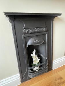 a black fireplace with a vase of flowers in it at Beach Lodge in Bournemouth