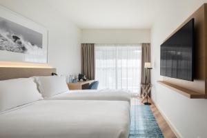 a hotel room with two beds and a flat screen tv at Crowne Plaza - Caparica Lisbon in Costa da Caparica