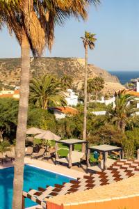 a pool with tables and chairs and palm trees at Belavista Da Luz - Wellness & Lifestyle Hotel in Luz