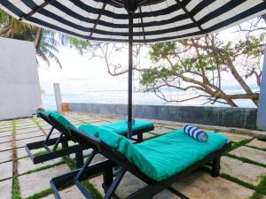 two chairs and an umbrella on the beach at Villa Thalpe Breeze in Unawatuna