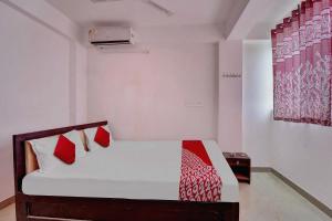 Schlafzimmer mit einem Bett mit roten und weißen Kissen in der Unterkunft OYO Flagship Hotel Celebrate Inn in Patna