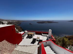 a red and white house with a view of the water at Hara's houses in Imerovigli