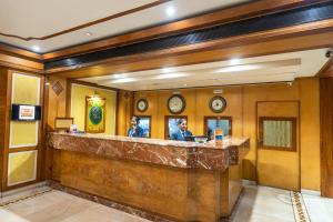 a lobby with a bar with two people sitting at it at Hotel Mayura in Raipur
