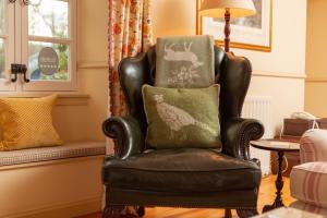 ein schwarzer Ledersessel mit einem grünen Kissen in einem Wohnzimmer in der Unterkunft Balnagown Estates Gardener's Cottage in Kildary