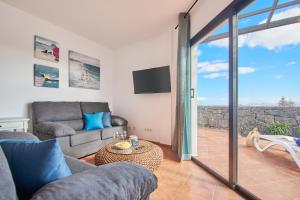 a living room with a couch and a table at Bungalow María de Timanfaya - Sea and Mountains Views, Pool, WiFi, 15 minutes walk to Marina Rubicón in Playa Blanca