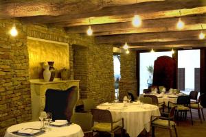 a restaurant with white tables and chairs and a brick wall at Archisa Relais Hostaria in Farigliano