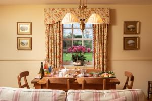 ein Esszimmer mit einem Tisch und einem Fenster in der Unterkunft Balnagown Estates Gardener's Cottage in Kildary