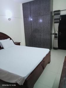 a bedroom with a bed and a wooden cabinet at Luxury Apartment in Karachi