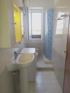 a white bathroom with a sink and a window at Blu Mariner in Vada +10 photos