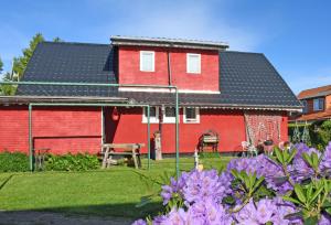 a red house with a black roof and some purple flowers at Pension im Seebad Breege in Drewoldke