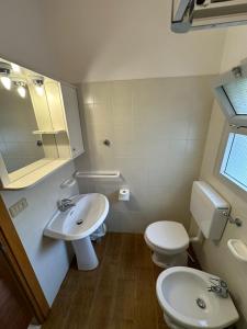 een badkamer met een wastafel, een toilet en een spiegel bij Marconi Bilocale - Agenzia Cocal in Caorle