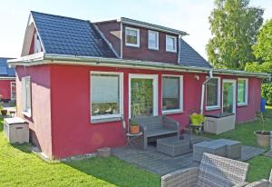 a small red house with a deck in the yard at Pension im Seebad Breege in Drewoldke