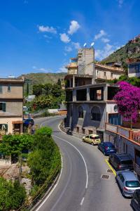 a winding road in a town with cars parked on it at Allegra Experience in Taormina