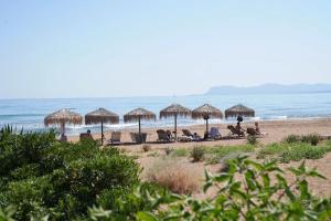 a beach with chairs and umbrellas and the ocean at Kostoula's House Beachfront by 8essentially in Stalos
